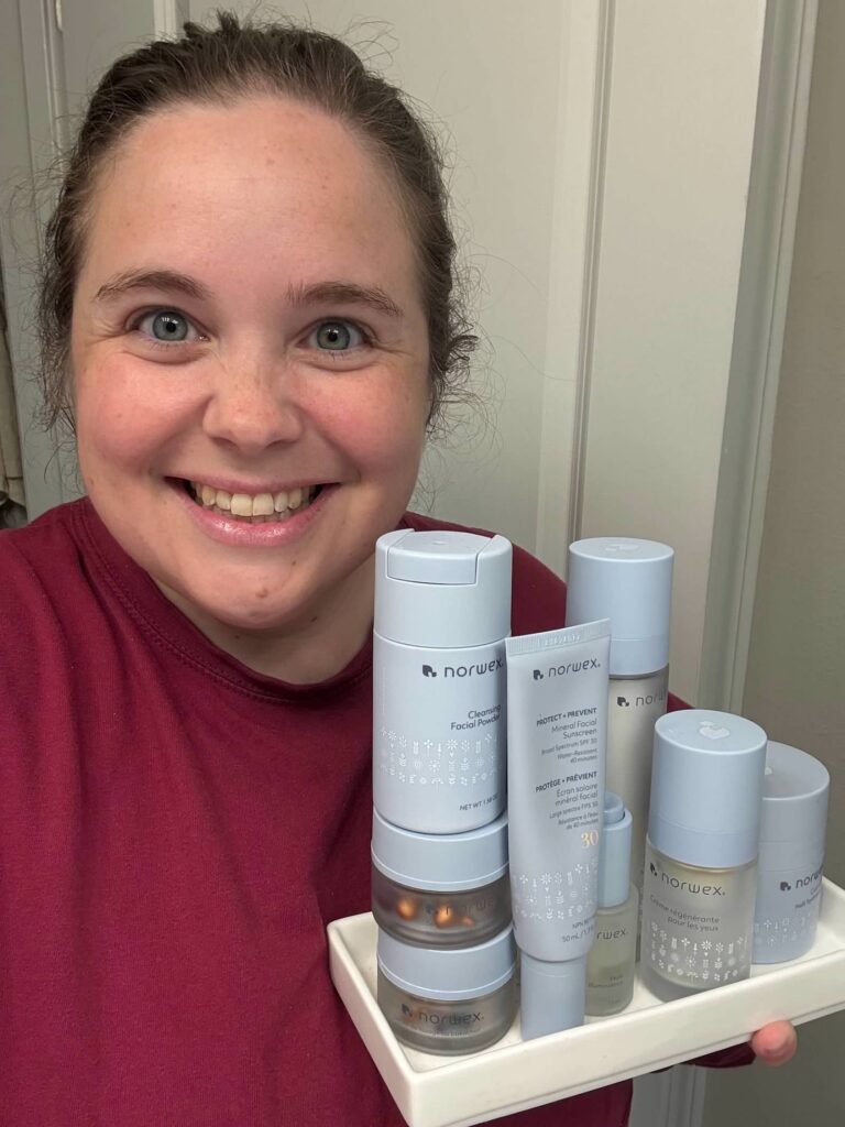 Emily Munns holding a collection of Norwex skincare products.
